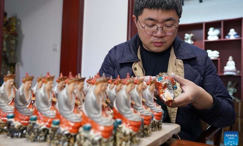 Zeng Rui checks cultural and creative products inspired by the Speechless Buddha at his studio in Jingdezhen, east China's Jiangxi Province, March 12, 2026.(Xinhua/Zhou Mi)

