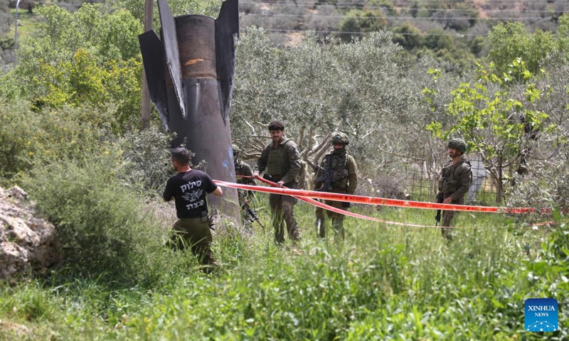 Israeli soldiers stand guard near the wreckage of a missile which fell in the town of Haris, north of Salfit in the West Bank, on March 24, 2026. (Photo by Nidal Eshtayeh/Xinhua)


