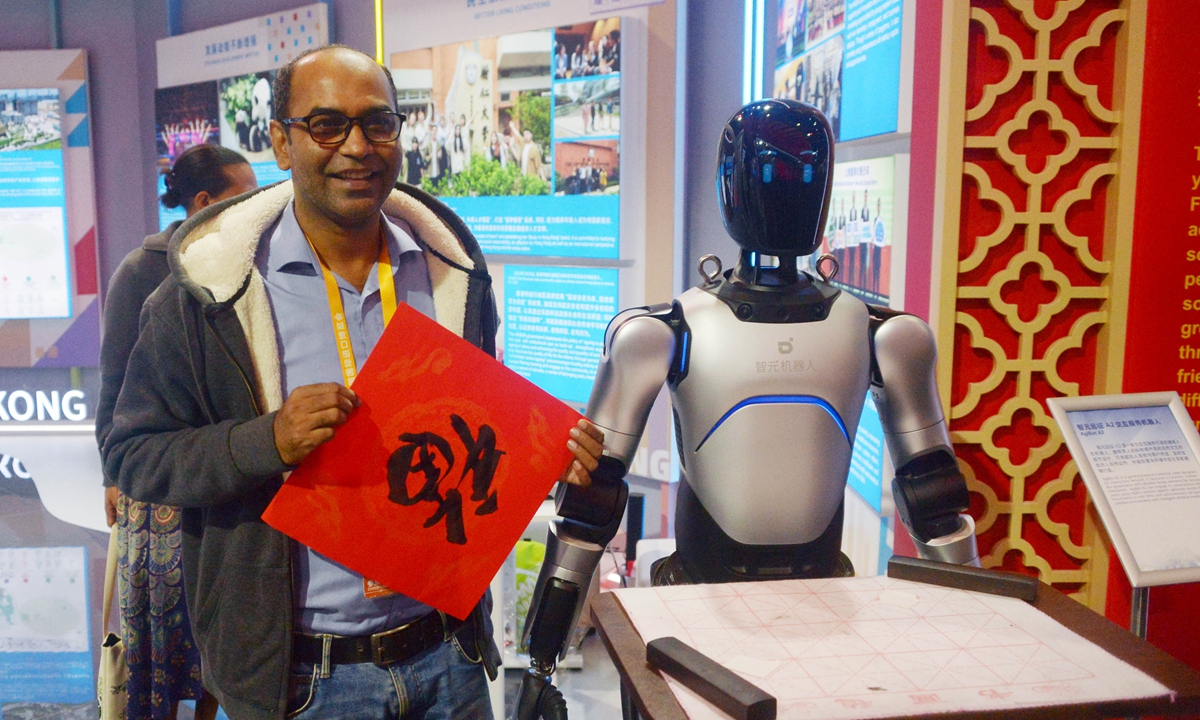 A foreign visitor experiences robot calligraphy during the 8th China International Import Expo in Shanghai on November 8, 2025. Photo: IC