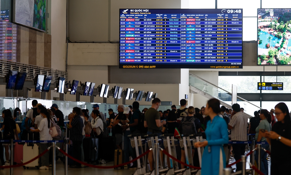 Passengers wait to check in at Noi Bai International Airport in Hanoi, Vietnam, on March 25, 2026. National carrier Vietnam Airlines plans to suspend operations on several routes, totaling 23 fl ights a week, starting April 1 due to fuel price hikes. Photo: VCG