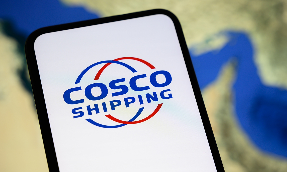 The logo of the shipping group COSCO appears on a smartphone screen with a satellite view of the Strait of Hormuz in the background. Photo: VCG