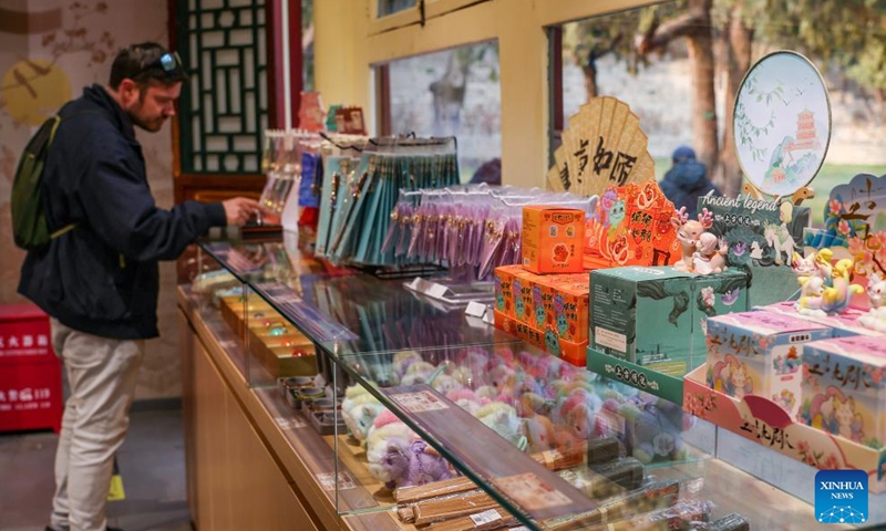 A man selects cultural and creative products at the Summer Palace in Beijing, capital of China, March 23, 2026. As temperature rises, multiple parks and scenic spots in Beijing have held spring-themed fairs and launched cultural and creative products, giving a nice boost to the spring economy. (Xinhua/Zhang Fan)

