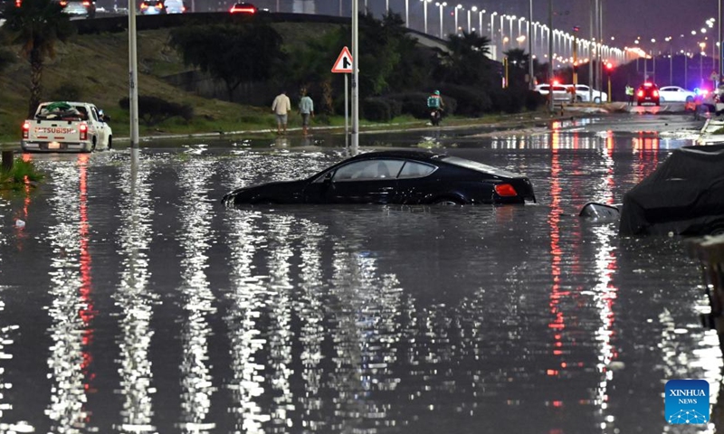 A car is stranded in water after heavy rain in Mubarak Al-Kabeer Governorate, Kuwait, March 25, 2026. Heavy rainfall and unstable weather conditions affected several parts of Kuwait on Wednesday. (Photo by Asad/Xinhua)


