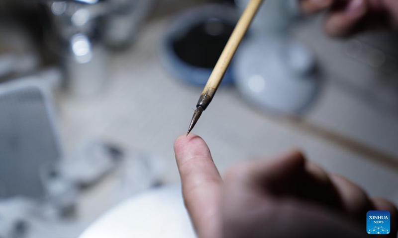 Cao Lang showcases a specialized brush for blue-and-white porcelain painting at the studio in Jingdezhen, east China's Jiangxi Province, March 11, 2026. (Xinhua/Zhou Mi)

