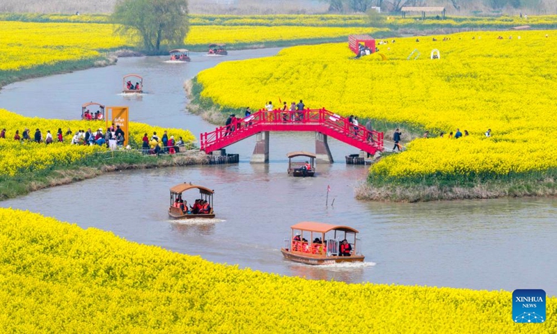 A drone photo taken on March 28, 2026 shows people taking boats to enjoy flowers at a scenic spot in Gaoyou, east China's Jiangsu Province. (Photo by Zhou Shegen/Xinhua)