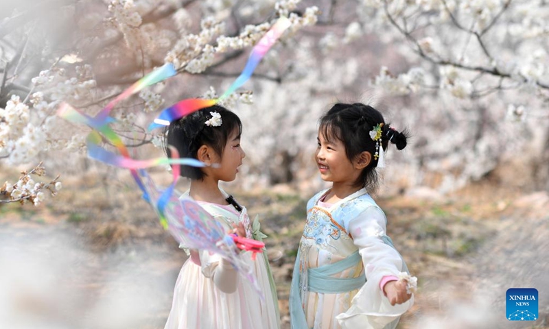Children play amid blossoms in Chengyang District of Qingdao, east China's Shandong Province, March 24, 2026. (Photo by Wang Haibin/Xinhua)
