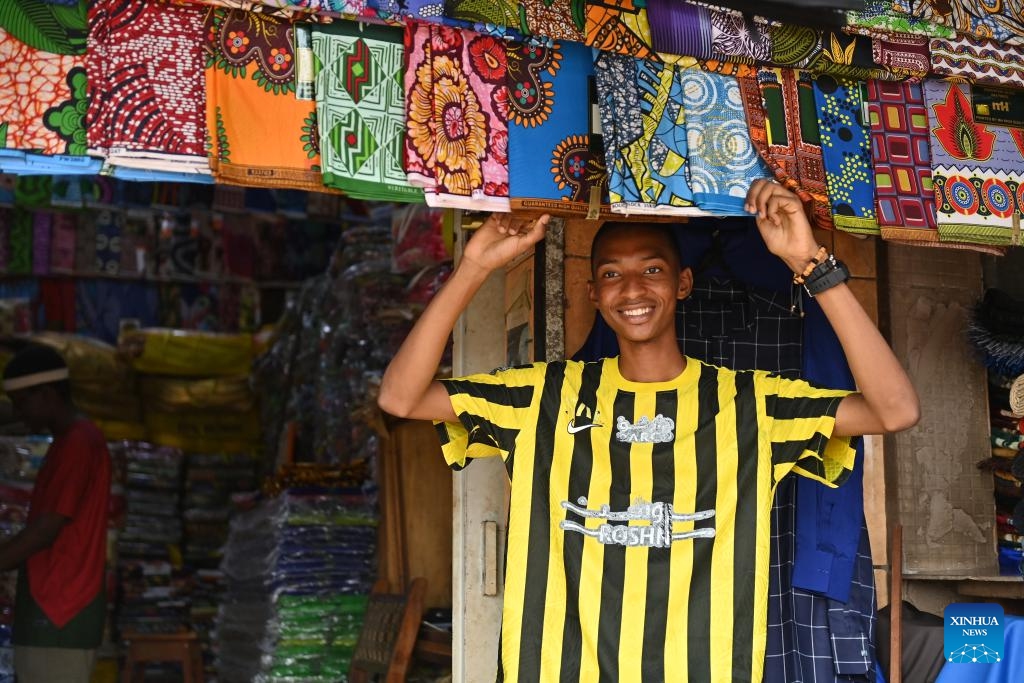 A merchant sells fabric outside a shop in Yaounde, Cameroon, on March 25, 2026. Situated in the hilly area of central Cameroon at an altitude of 750 meters, Yaounde is the capital and second-largest city of Cameroon. (Xinhua/Liu Qiong)