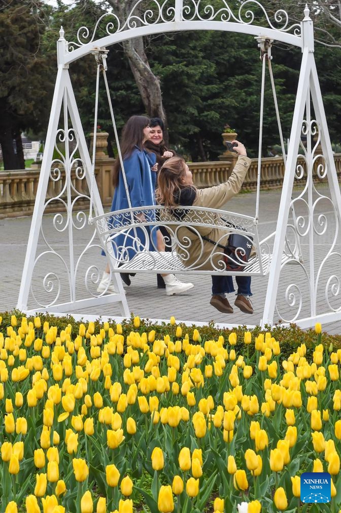 A woman sitting on a swing takes selfies in Baku, Azerbaijan, March 29, 2026. (Xinhua/Chen Junfeng)
