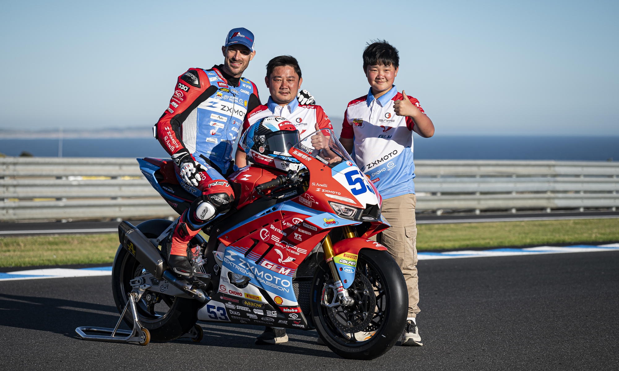 Zhang Xue (center) poses for a photo with his son (right) and motobike racing driver Valentin Debise.