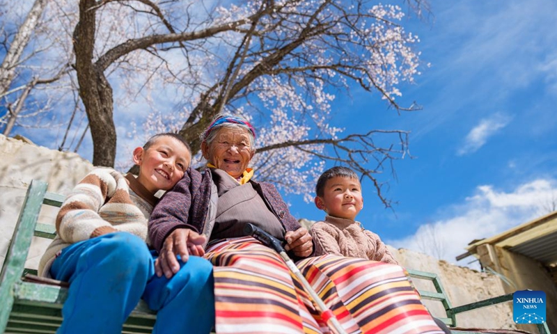 Tsering Sangmo (C) and her great-grandsons sit in her yard in Zongkhar Village of Shannan City, southwest China's Xizang Autonomous Region, March 26, 2026.(Xinhua/Tenzin Nyida)
