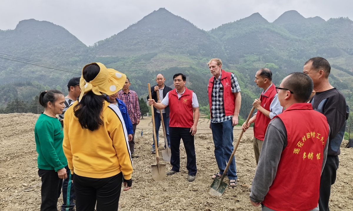 Members of the village-based work team, wearing red vests, explain key points regarding passion fruit cultivation to the villagers in Lianhua village, Hechi, in April 2024. Photo: Courtesy of Xie Wanju