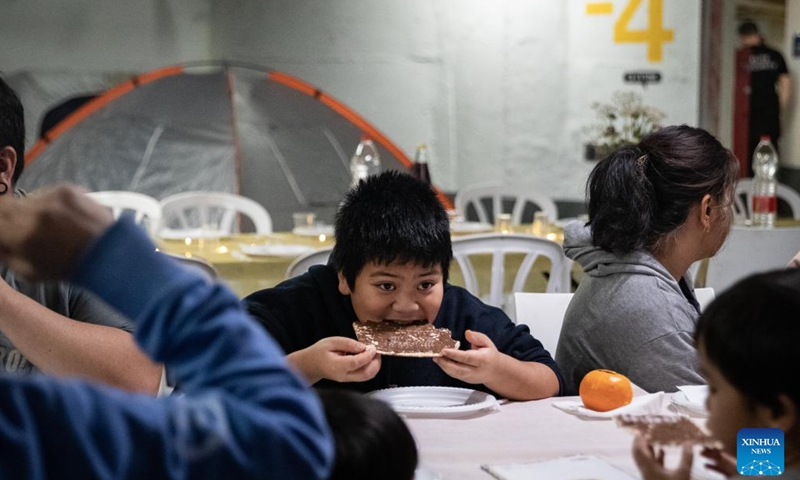 A boy eats Matzo, or unleavened bread, during a Passover Seder at an underground shelter in Tel Aviv, Israel, April 1, 2026. The week-long Jewish holiday of Passover began at sunset on April 1 and will end at sunset on April 8. As the military conflict continues, some Israelis chose to observe the traditional holiday meal in protective facilities. (Xinhua/Chen Junqing)

