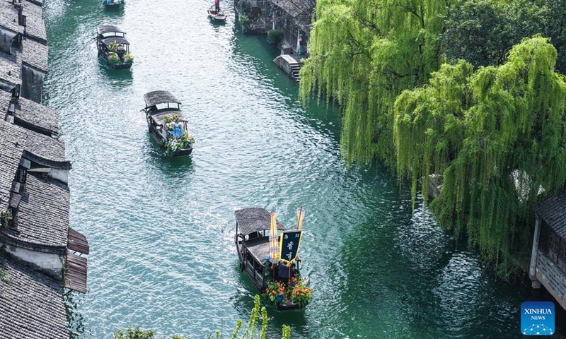 An aerial drone photo taken on April 1, 2026 shows a boat parade during a folk fair in Wuzhen, Tongxiang City, east China's Zhejiang Province. A folk fair opened here on Wednesday, during which people can experience the atmosphere of traditional sericulture and enjoy the spring scenery through folk parades both on the street and on the water. (Xinhua/Xu Yu)

