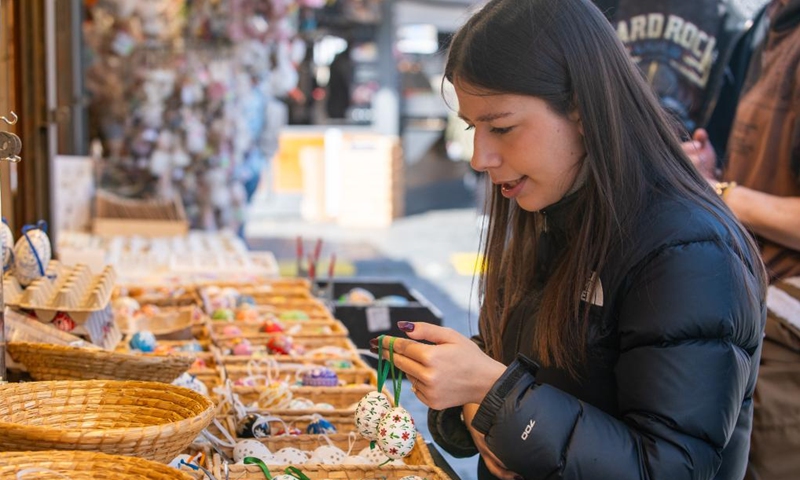 A woman buys festive decorations at an Easter market in Prague, the Czech Republic, April 2, 2026. As Easter approaches, a market is held in Prague's old city, attracting residents and tourists to experience the festive atmosphere. (Photo by Dana Kesnerova/Xinhua)