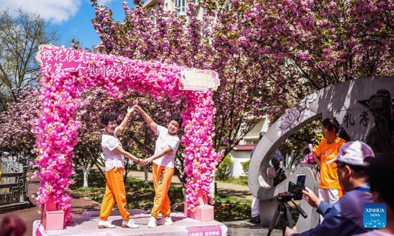 People pose for photos under cherry blossoms along the Shuicheng River in Liupanshui, southwest China's Guizhou Province, April 3, 2026. The cherry blossoms along the Shuicheng River in Liupanshui are in full bloom, attracting people for spring outings. In recent years, the city has leveraged its riverside cherry blossoms to expand the flower-viewing industry, unlocking market consumption potential with its natural landscapes. (Xinhua/Tao Liang)
