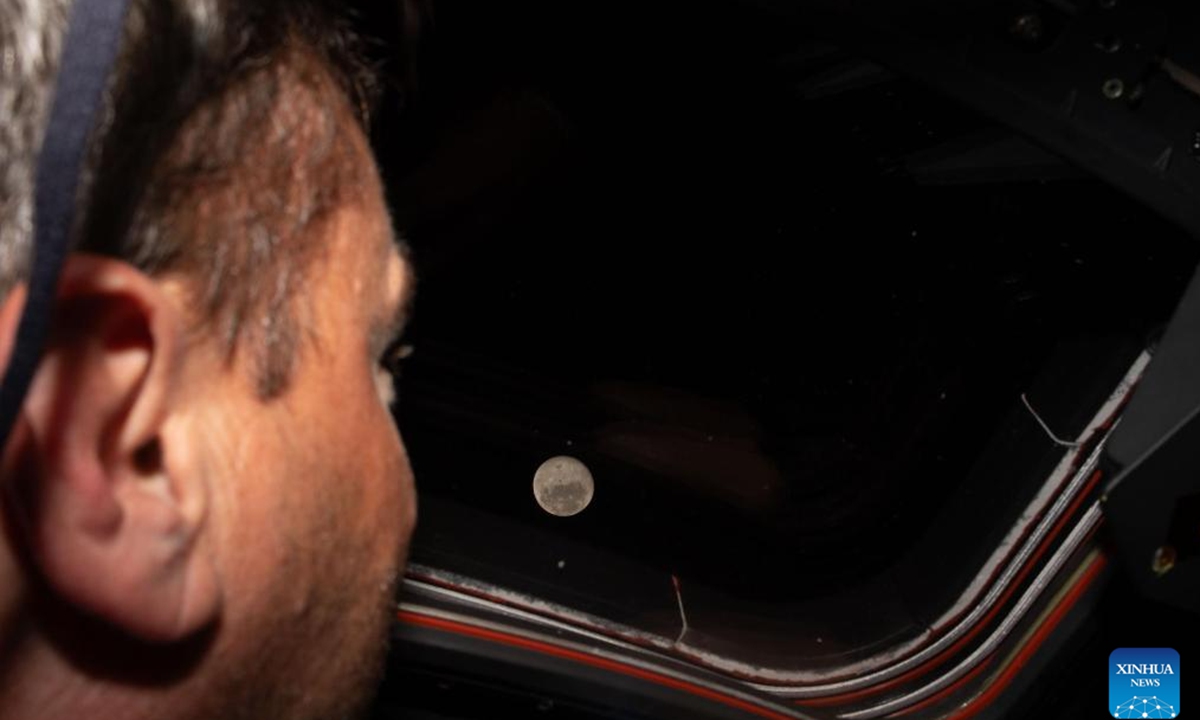 NASA astronaut Reid Wiseman looks out one of the Orion spacecraft's main cabin windows at the Moon, on April 6, 2026. The crew of the Artemis II mission on Monday broke the record for the farthest distance from Earth ever traveled by humans, surpassing the milestone achieved by Apollo 13 in April 1970, according to NASA. (NASA/Handout via Xinhua)