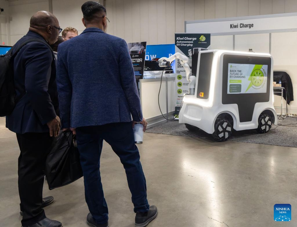 Participants view an autonomous electric vehicle (EV) charging vehicle during the EV & Charging Expo 2026 in Toronto, Canada, on April 8, 2026. Exploring electric vehicles and charging solutions for fleets, buildings and commercial sites, the two-day event kicked off here on Wednesday, with about 2,000 attendees from more than 800 organizations. (Photo by Zou Zheng/Xinhua)

