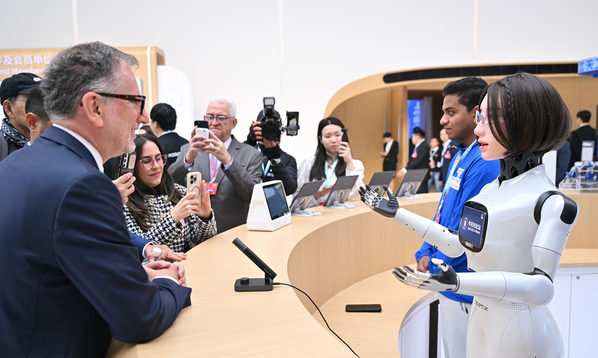 A foreign guest interacts with a Chinese-developed robot at the 2026 Zhongguancun Forum on March 25, 2026. Photo: VCG