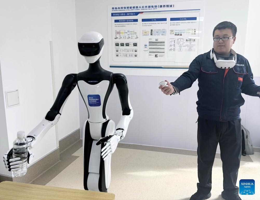 This photo taken on March 18, 2026 shows a robot learning to grab object in the guidance of a coach at the Qingdao Training Center for Elderly Care Robots in Qingdao, east China's Shandong Province. (Xinhua)