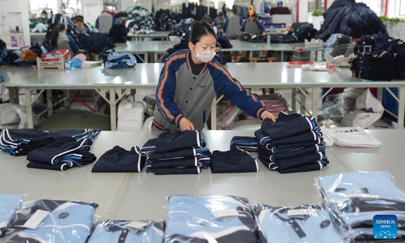 A staff member arranges school uniforms for packing at a children's clothing company in Zhili Town, Huzhou City of east China's Zhejiang Province, April 13, 2026.