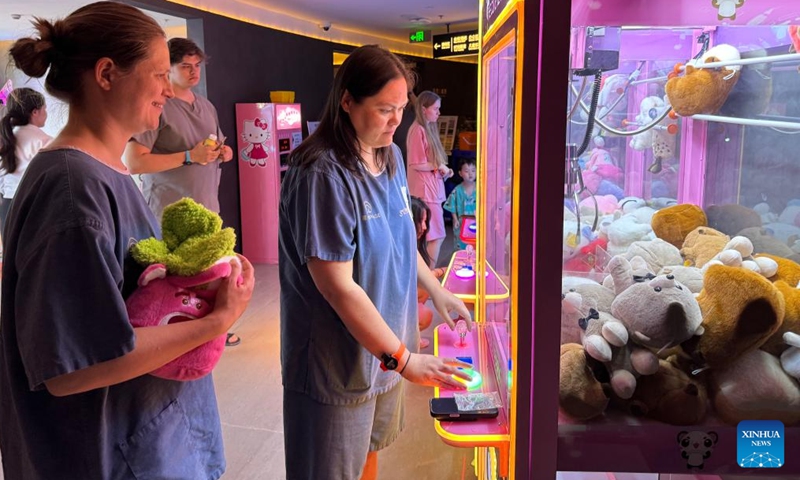 Foreign tourists play with a claw machine at a hot spring resort in Shanghai, east China, April 3, 2026. (Xinhua/Huang Anqi)

