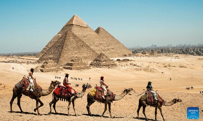 Tourists ride camels in the Giza Pyramids scenic spot in Giza, Egypt, April 9, 2026. The Giza Pyramids located southwest of Cairo, capital of Egypt, are one of the most representative sites of ancient Egyptian civilization. The complex includes the three pyramids known as the Great Pyramids, the massive sculpture known as the Great Sphinx, and several ancient cemeteries and smaller pyramids. The pyramids are part of a UNESCO World Heritage Site inscribed in 1979. (Xinhua/Xin Mengchen)