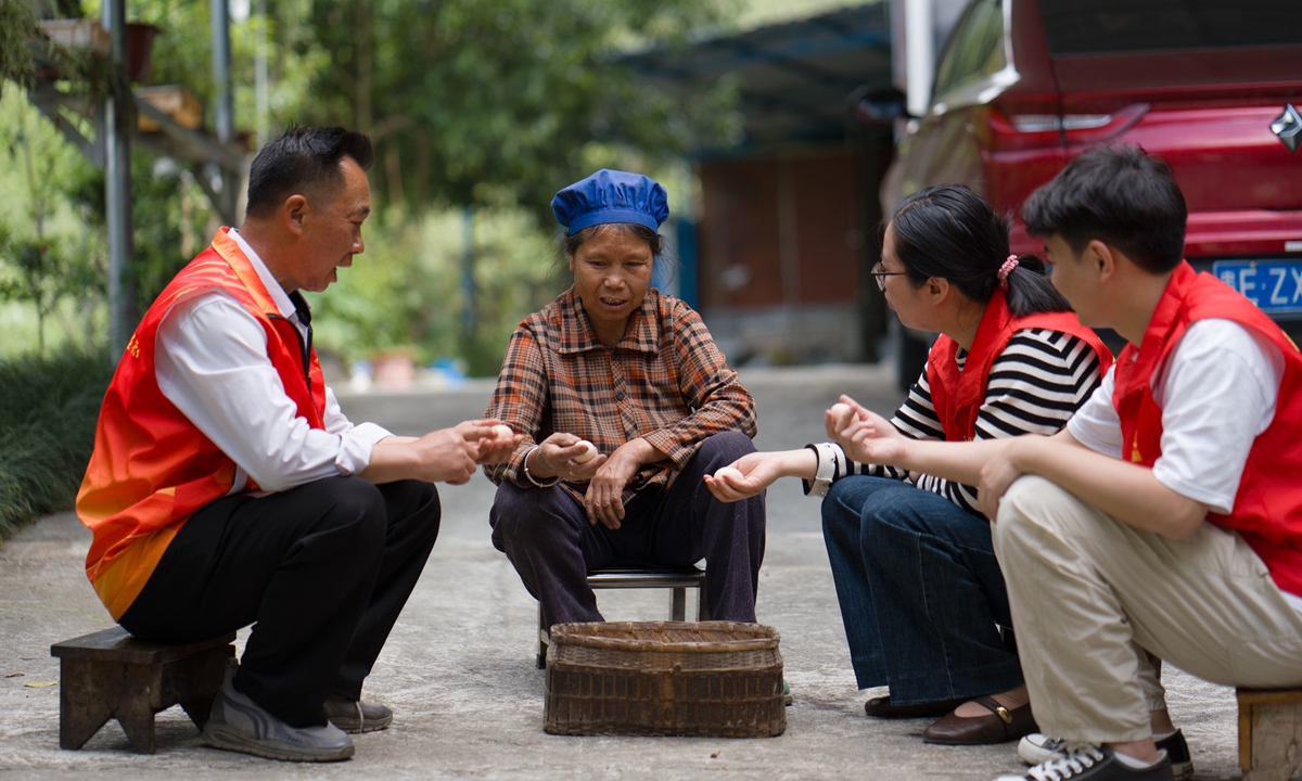 Village officials in red vests sit together with a farmer whose free-range eggs they are helping to sell in a village in Wangmo County, Guizhou Province, on April 10, 2025.