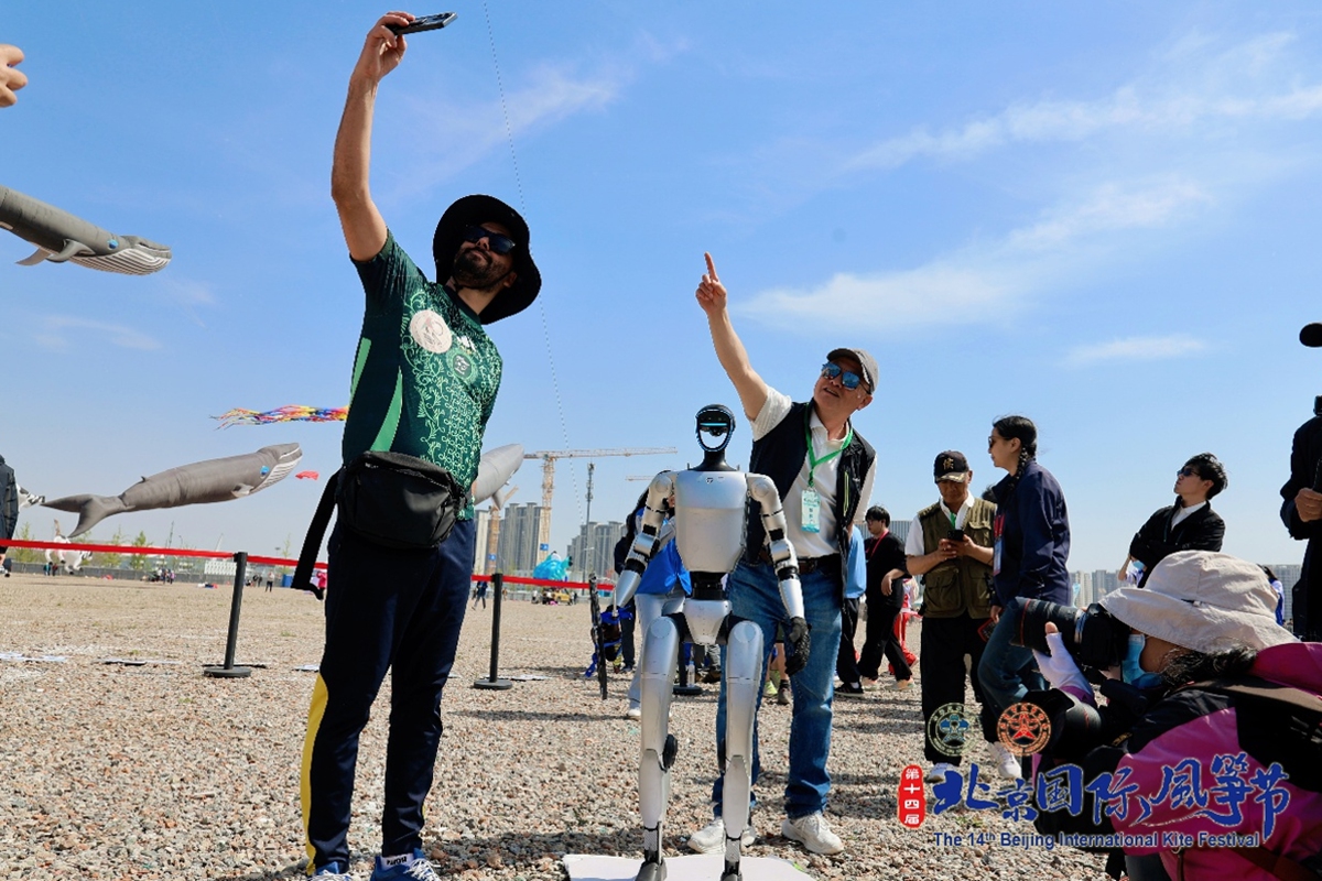 A foreign competitor poses for a photo with a robot at the 14th Beijing International Kite Festival in Beijing on April 11, 2026. Photo: Courtesy of Beijing Sports Federation