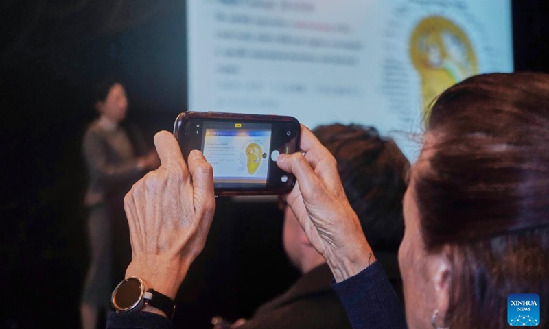 An audience takes photos of a screen display at the Chinese + TCM South Island Roadshow in Christchurch, New Zealand, April 11, 2026. The Chinese + TCM (traditional Chinese medicine) South Island Roadshow was held here on Saturday. A team from Zhejiang Chinese Medical University engaged local audiences with lectures, interactive demonstrations and hands-on activities during the event. (Photo by Chen Siyumeng/Xinhua)