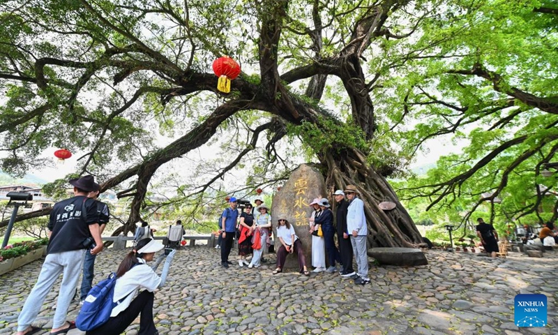 Tourists pose for a photo at Yunshuiyao ancient town in Nanjing County, southeast China's Fujian Province, April 9, 2026. Tulou, the unique residential architecture of Fujian Province, was inscribed on the UNESCO's World Heritage List in 2008. In recent years, local authorities has continued promoting Tulou protection, revitalization, and integration with tourism. (Xinhua/Lin Shanchuan)