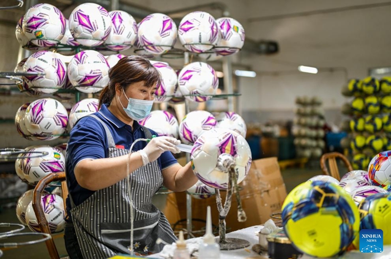 An employee works on a football at a workshop in Taizhou City, east China's Zhejiang Province, April 10, 2026. In recent years, Taizhou City has encouraged the cluster development of its sports goods manufacturing industry, forming several clusters including outdoor jackets, outdoor leisure products, sports glasses, and cycling and related outdoor products. (Xinhua/Jiang Han)