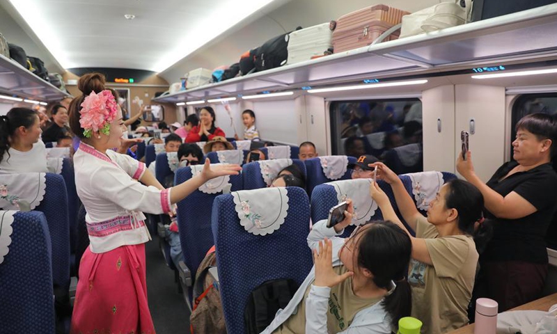 Stewardesses interact with passengers aboard train No. D86 from Kunming, capital city of southwest China's Yunnan Province, to the Lao capital Vientiane, July 18, 2025. (Photo by Yang Zixuan/Xinhua)