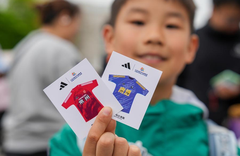 A boy shows cards of the official jersey of the two teams before the opening match. (Xinhua/Li Bo)
