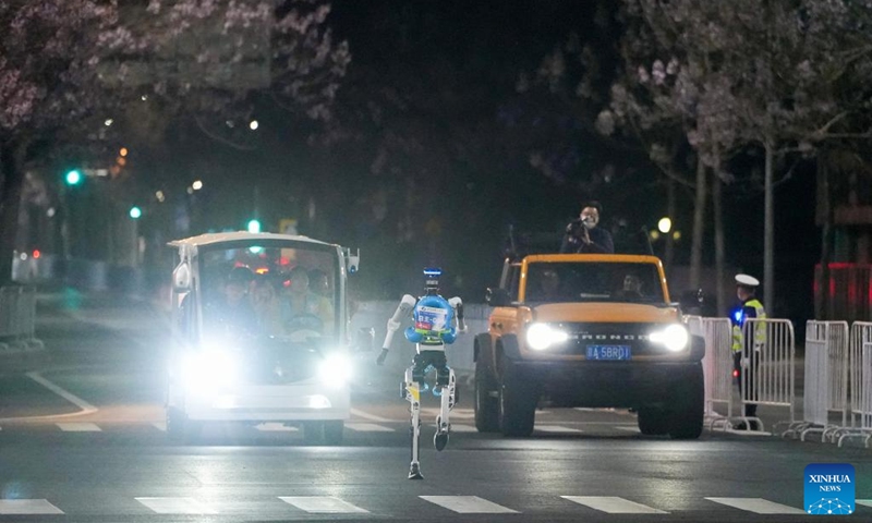 A humanoid robot runs during the test activity for the 2026 Beijing E-Town Humanoid Robot Half Marathon on April 11, 2026. A full-process and comprehensive testing activity for the Beijing E-Town humanoid robot half-marathon, scheduled for April 19, 2026, was carried out from Saturday night to early Sunday morning. (Xinhua/Ju Huanzong)