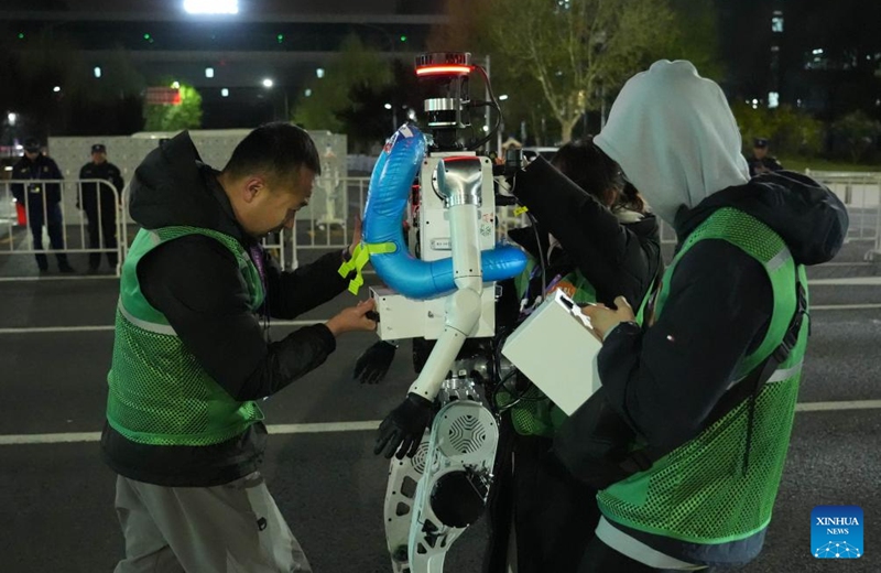 Engineers change batteries for a humanoid robot during the test activity for the 2026 Beijing E-Town Humanoid Robot Half Marathon on April 11, 2026. A full-process and comprehensive testing activity for the Beijing E-Town humanoid robot half-marathon, scheduled for April 19, 2026, was carried out from Saturday night to early Sunday morning. (Xinhua/Xie Han)
