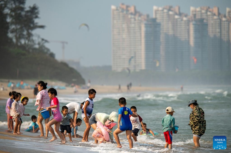 People have fun on the seashore in Qionghai City, south China's Hainan Province, April 12, 2026. (Photo by Meng Zhongde/Xinhua)