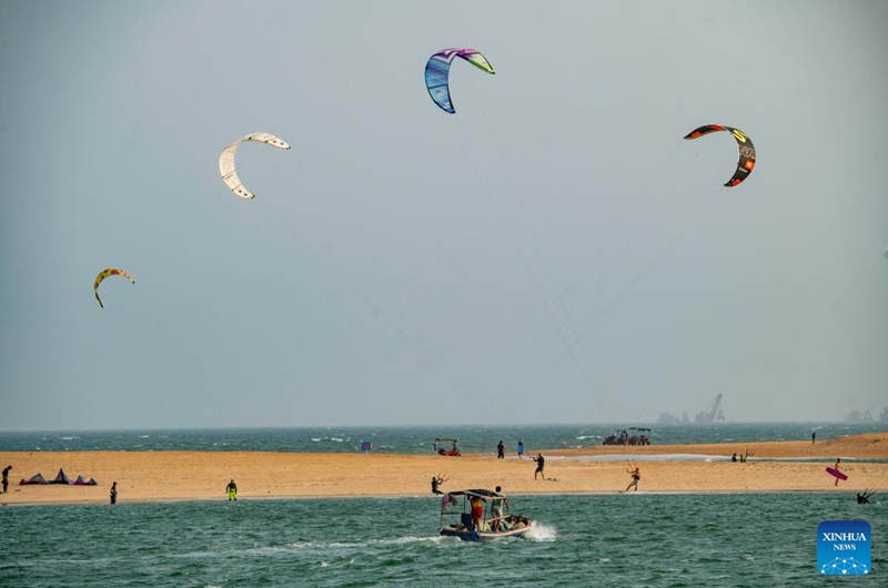 People have fun on the seashore in Qionghai City, south China's Hainan Province, April 12, 2026. (Photo by Meng Zhongde/Xinhua)