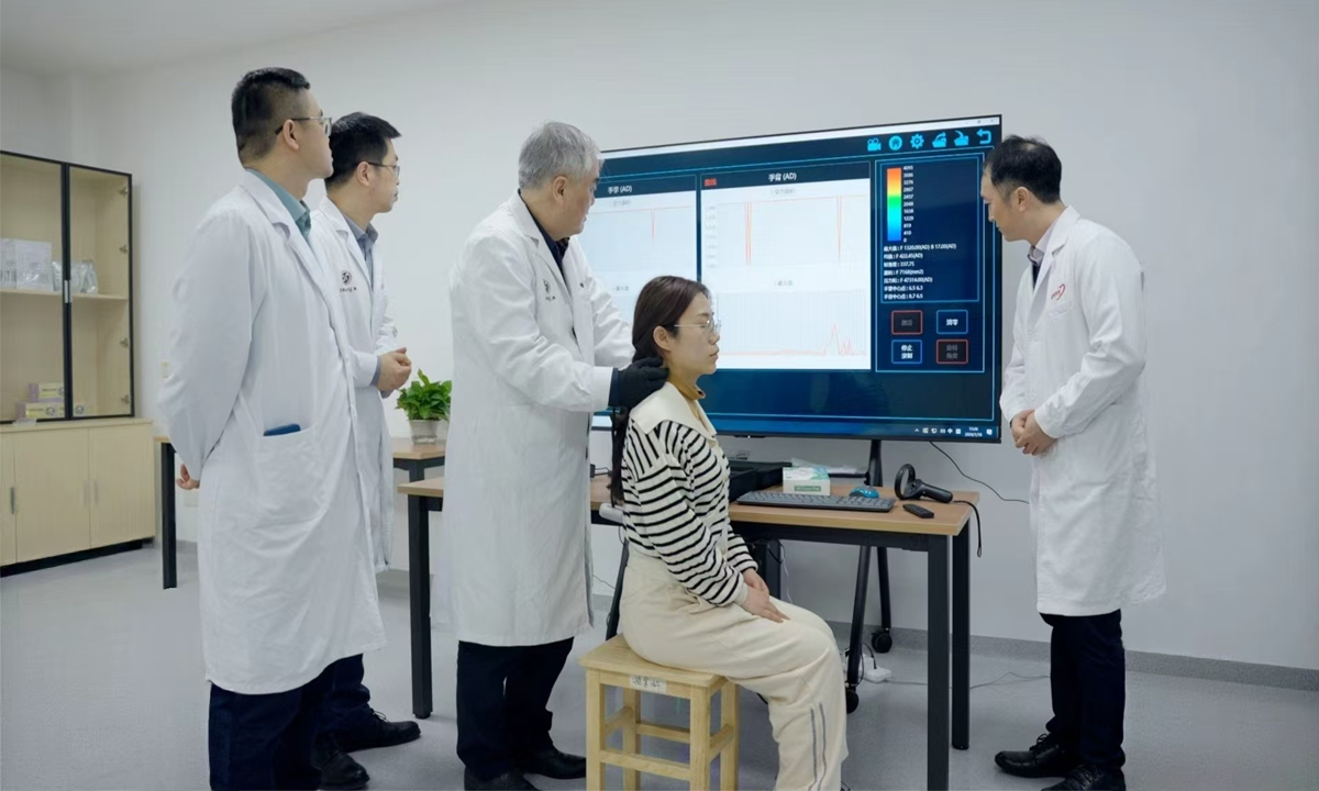 Fang Min (third from the left) pilots an AI equipment to perform tuina on a patient. Photo: Courtesy of Fang