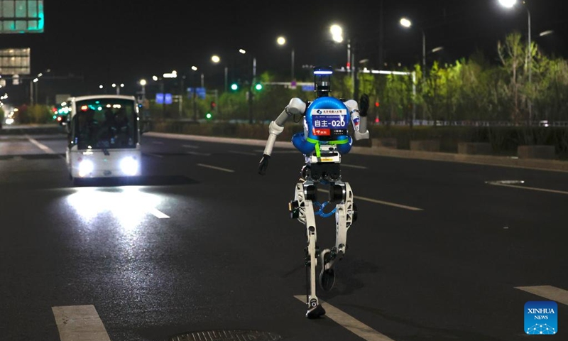 A humanoid robot from remote control team runs during the test activity for the 2026 Beijing E-Town Humanoid Robot Half Marathon on April 11, 2026. A full-process and comprehensive testing activity for the Beijing E-Town humanoid robot half-marathon, scheduled for April 19, 2026, was carried out from Saturday night to early Sunday morning. (Photo by Zhai Yifan/Xinhua)