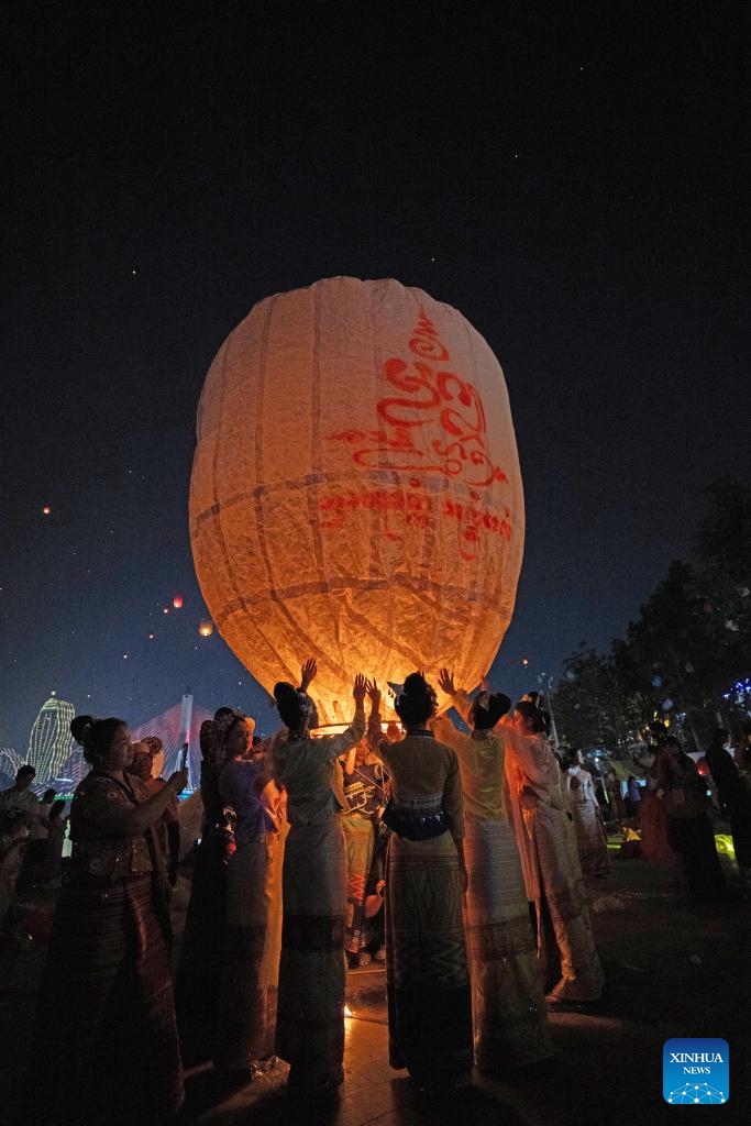 People fly Kongming lanterns, a kind of small hot-air paper balloon, by the Lancang River in Jinghong City, Xishuangbanna Dai Autonomous Prefecture, southwest China's Yunnan Province, April 13, 2026. (Xinhua/Jiang Wenyao)