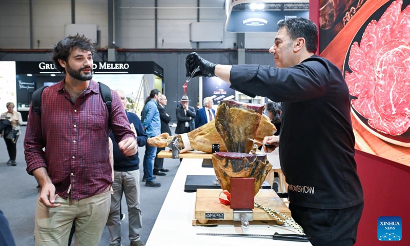 An exhibitor gives a visitor a sample of cecina during the Salon Gourmets in Madrid, Spain, on April 13, 2026. The 39th Salon Gourmets will run in Madrid from April 13 to 16. (Photo by Gustavo Valiente/Xinhua)