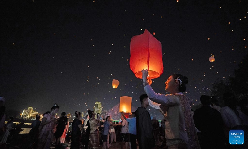 People fly Kongming lanterns, a kind of small hot-air paper balloon, by the Lancang River in Jinghong City, Xishuangbanna Dai Autonomous Prefecture, southwest China's Yunnan Province, April 13, 2026. (Xinhua/Jiang Wenyao)