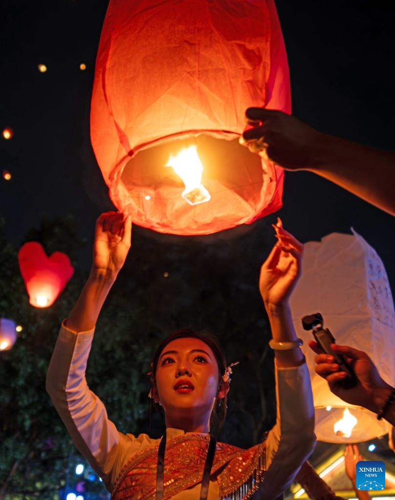 People fly Kongming lanterns, a kind of small hot-air paper balloon, by the Lancang River in Jinghong City, Xishuangbanna Dai Autonomous Prefecture, southwest China's Yunnan Province, April 13, 2026. (Xinhua/Jiang Wenyao)