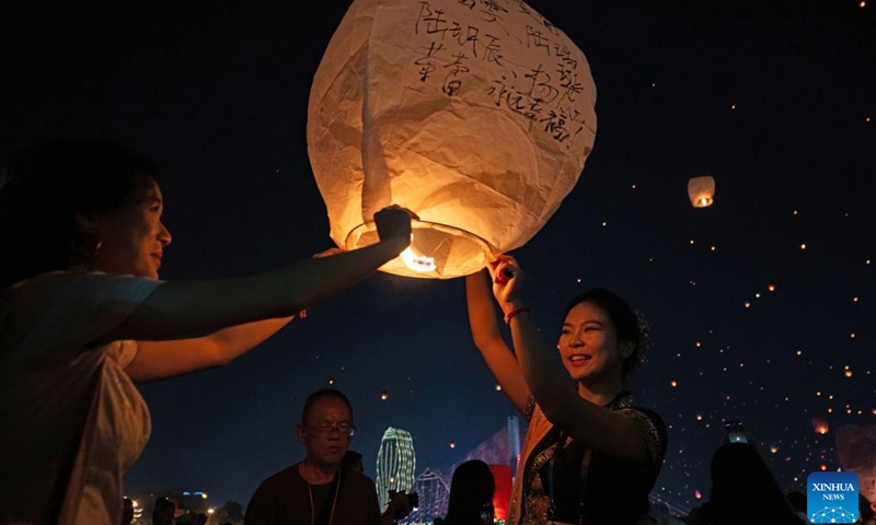 People fly Kongming lanterns, a kind of small hot-air paper balloon, by the Lancang River in Jinghong City, Xishuangbanna Dai Autonomous Prefecture, southwest China's Yunnan Province, April 13, 2026. (Xinhua/Jiang Wenyao)