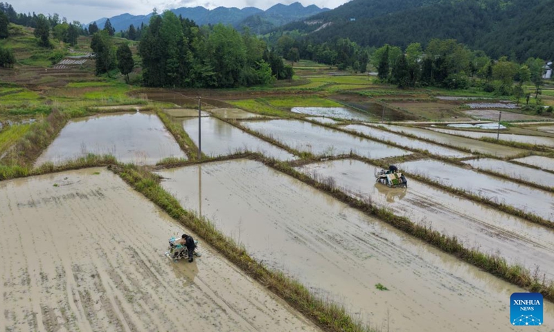 An aerial drone photo taken on May 7, 2026 shows farmers working in the fields in Yuchi Town of Shizhu Tujia Autonomous County in Chongqing, southwest China. Yuchi Town, a typical agricultural town with an average altitude of 1,000 meters, has built more than 13,000 mu (866.67 hectares) of high-standard farmland in recent years, becoming the first batch of demonstration plots for high-standard farmland transformation in the city's alpine and hilly areas. The town's annual output of high-quality paddy rice exceeds 3,700 tons. (Xinhua/Tang Yi)