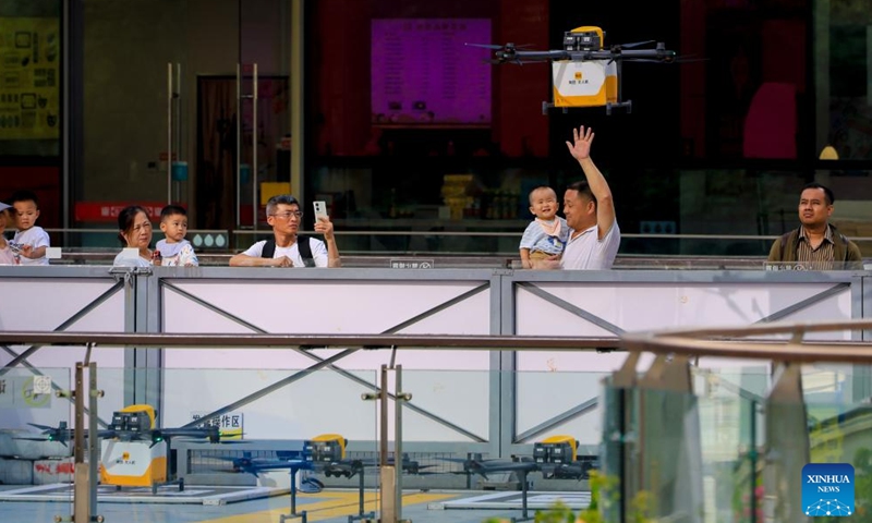 People watch a drone delivering takeout food at a drone takeoff point of Meituan, a major online lifestyle platform in China, in Shenzhen, south China's Guangdong Province, May 6, 2026. South China's tech hub of Shenzhen now stands as a leading manufacturing base for unmanned aerial vehicles, producing 70 percent of China's consumer drones and 50 percent of its industrial drones.(Xinhua/Mao Siqian)

