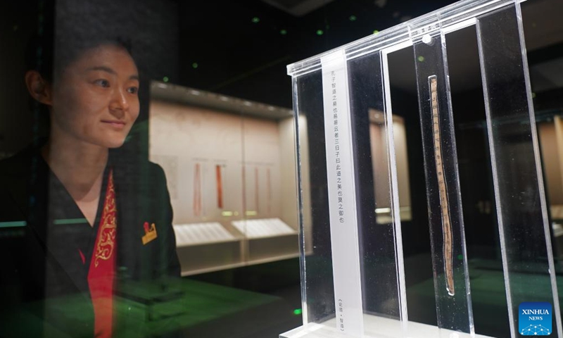 An exhibition docent views a bamboo slip written with manuscripts of a once lost chapter of The Analects of Confucius at the Nanchang Relic Museum of Haihun Marquisate of Han Dynasty in Nanchang, east China's Jiangxi Province, April 13, 2026. 