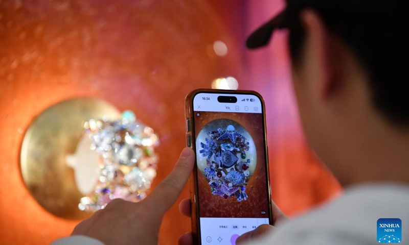 A man takes a photo of an exhibit during the Watches and Wonders Geneva 2026 at the Palexpo in Geneva, Switzerland, April 14, 2026. The 7-day event kicked off here on Tuesday, bringing together 65 participating brands. (Xinhua/Lian Yi)


