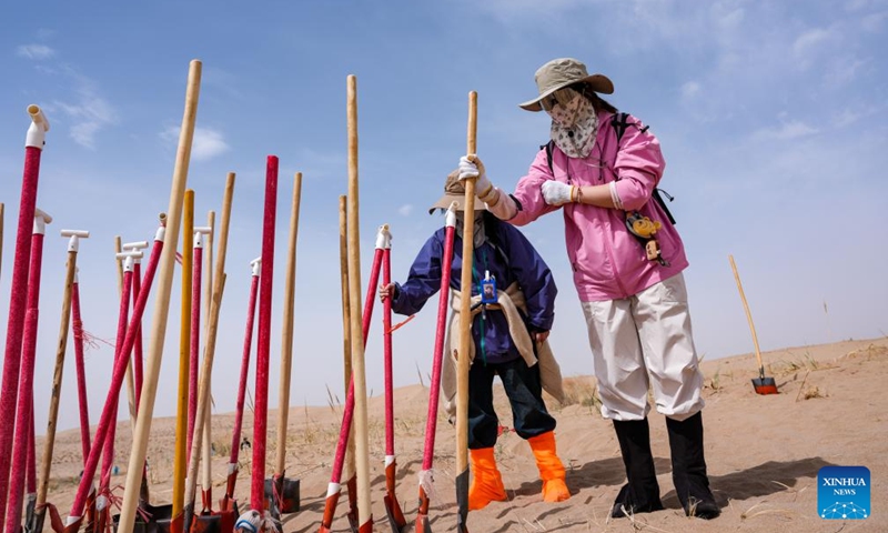 Volunteers insert shovels into the designated area after work at the Zhonglin ecological public welfare forest base of Minqin County, northwest China's Gansu Province, April 21, 2026.

