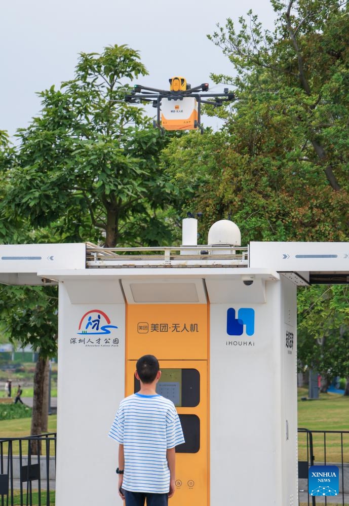 A tourist waits for takeout food delivered by a drone in front of a pickup kiosk in Shenzhen Talent Park in Shenzhen, south China's Guangdong Province, April 1, 2026. South China's tech hub of Shenzhen now stands as a leading manufacturing base for unmanned aerial vehicles, producing 70 percent of China's consumer drones and 50 percent of its industrial drones.(Xinhua/Mao Siqian)

